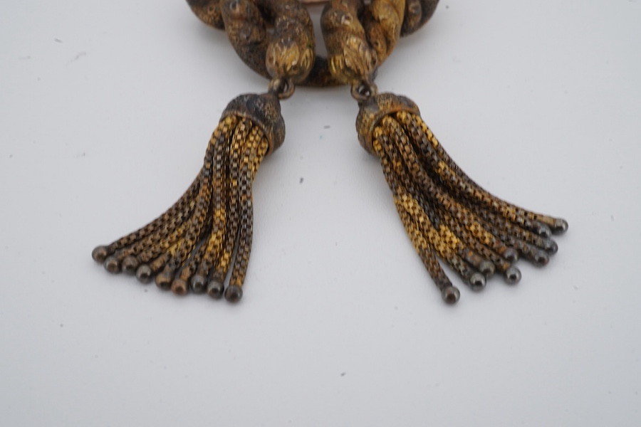 A Victorian opal brooch, mid 19th century, of knotted design in textured gold, set with a cabochon opal, suspending two tassels, length 7cm, gross weight 14 grams